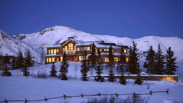 A large, multi-story lodge with a prominent entrance and a snow-covered landscape in the background. - Silver Lane (Mt. Crested Butte)