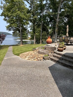 A patio area with a stone pathway leading to a seating area with outdoor furniture and a large decorative urn.