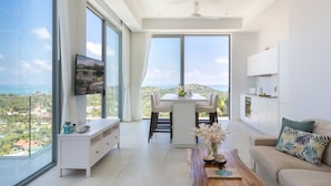Un salon moderne avec un coin repas, de grandes fenêtres et une vue sur la mer.