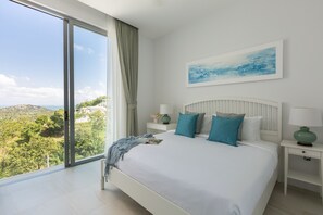 Ein Schlafzimmer mit einem großen Bett, Blick ins Freie und einem Bild an der Wand.