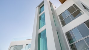 Un bâtiment moderne doté de grandes fenêtres et d’une façade blanche et épurée.