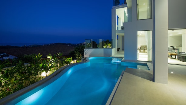 Une maison moderne dotée d’une piscine, de grandes fenêtres et offrant une vue sur le paysage.