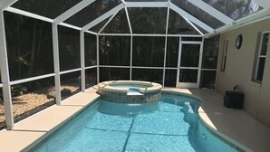 A swimming pool with a hot tub, surrounded by a covered patio with large windows. - 5⭐️ LUXURY BEACH VILLA with SECLUDED HEATED POOL+HOT TUB SURROUNDED by PALM TREES (Naples)