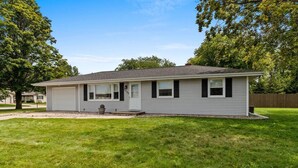 A single-story house with a garage, a front porch, and a well-maintained lawn. - Walk-to-Lambeau Tailgate House (Green Bay)