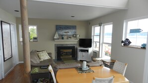 A cozy living room with a fireplace, a television, and a dining area with a wooden table and chairs.