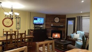 Una sala de estar con chimenea, televisor y comedor con muebles de madera.