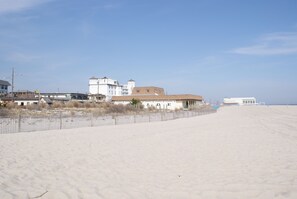 Een strand met een hek, gebouwen en een heldere lucht.