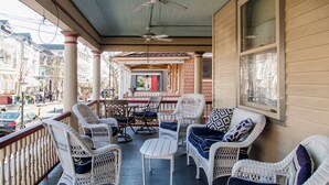 A porch with wicker furniture, a table, and a ceiling fan. - Stay in the Heart of Cape May at the Charming Rose Suite (Cape May)