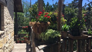 A wooden deck with potted plants and flowers. - Romantic Rock Cabin, Beautiful, Spectacular Views of Frio River & Mountains! (Concan)
