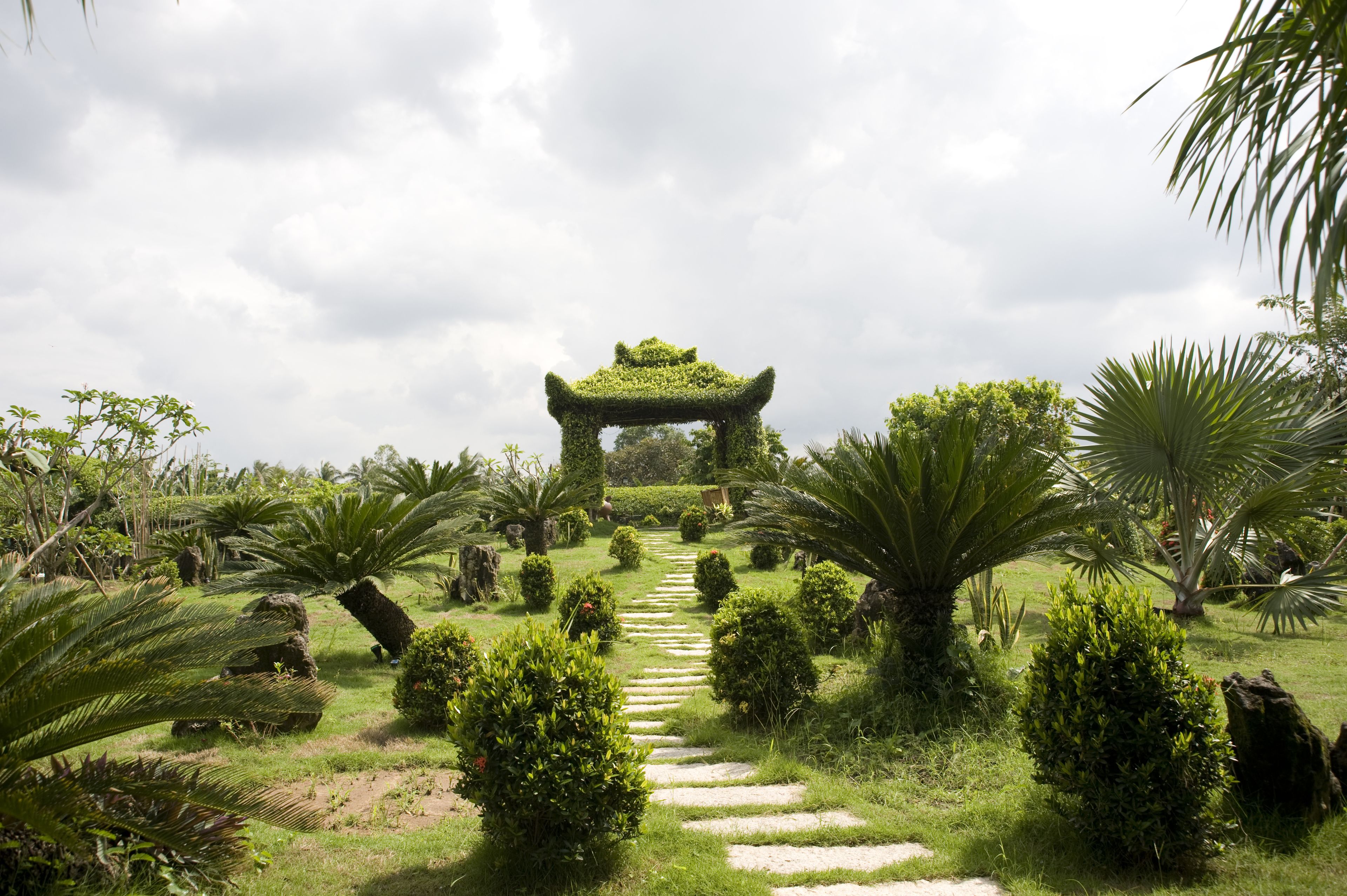 Un jardín con un sendero de piedra que lleva a un arco tradicional.