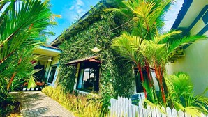 A house with a covered porch, surrounded by lush greenery and a white picket fence. - Forever Green Resort (Phu Tuc)