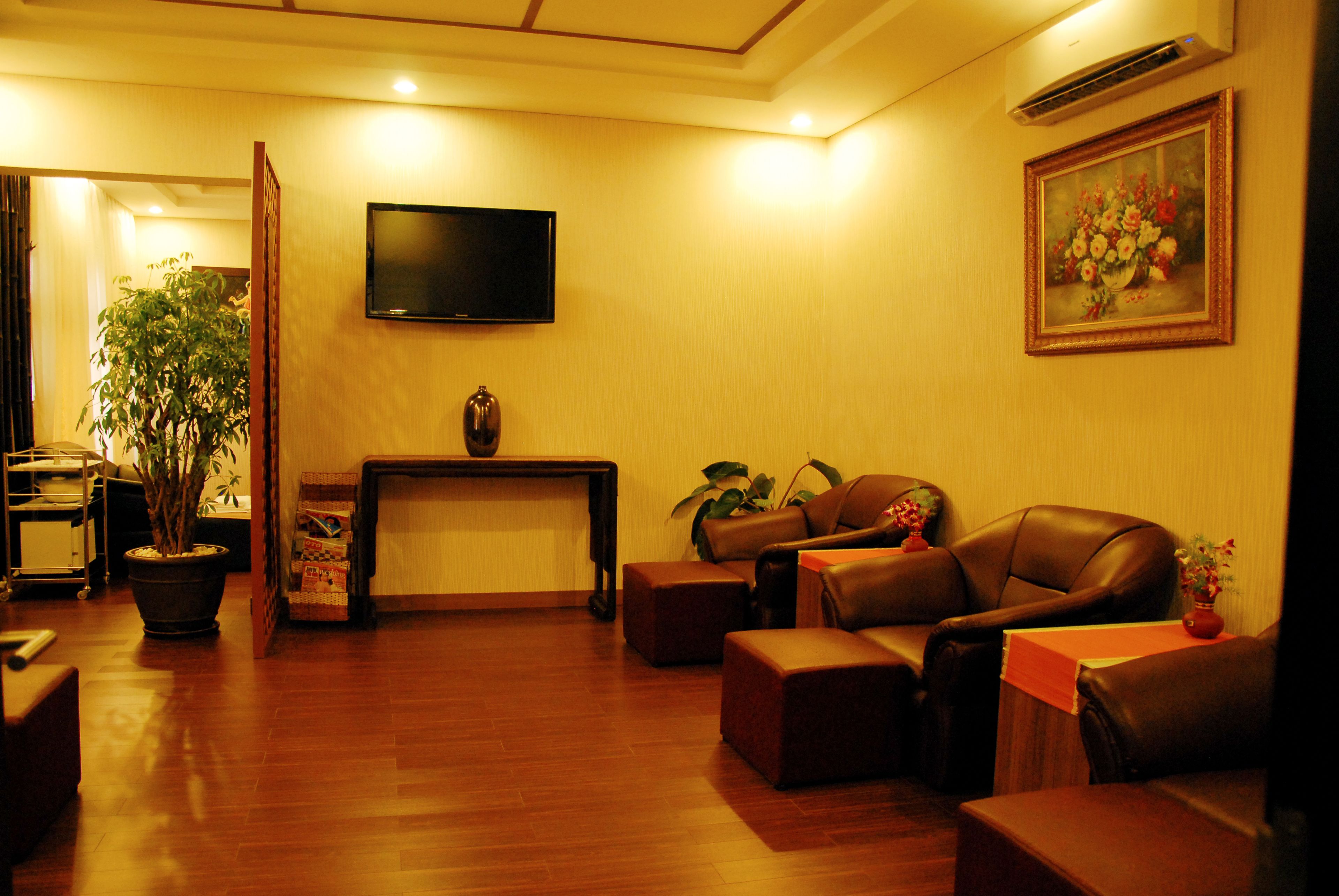 A living room with a flat-screen TV, leather sofas, a coffee table, a fireplace, and a potted plant.