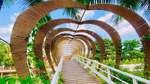 A wooden bridge with a white railing, surrounded by lush greenery and palm trees. - Forever Green Resort (Phu Tuc)