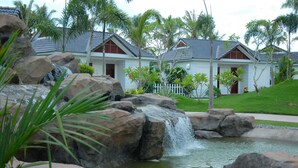 A resort with a waterfall, large rocks, and a white fence. - Forever Green Resort (Phu Tuc)