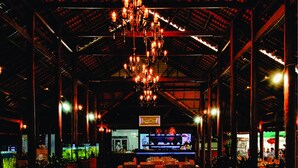 A spacious restaurant with high ceilings, wooden tables and chairs, and a central chandelier. - Forever Green Resort (Phu Tuc)