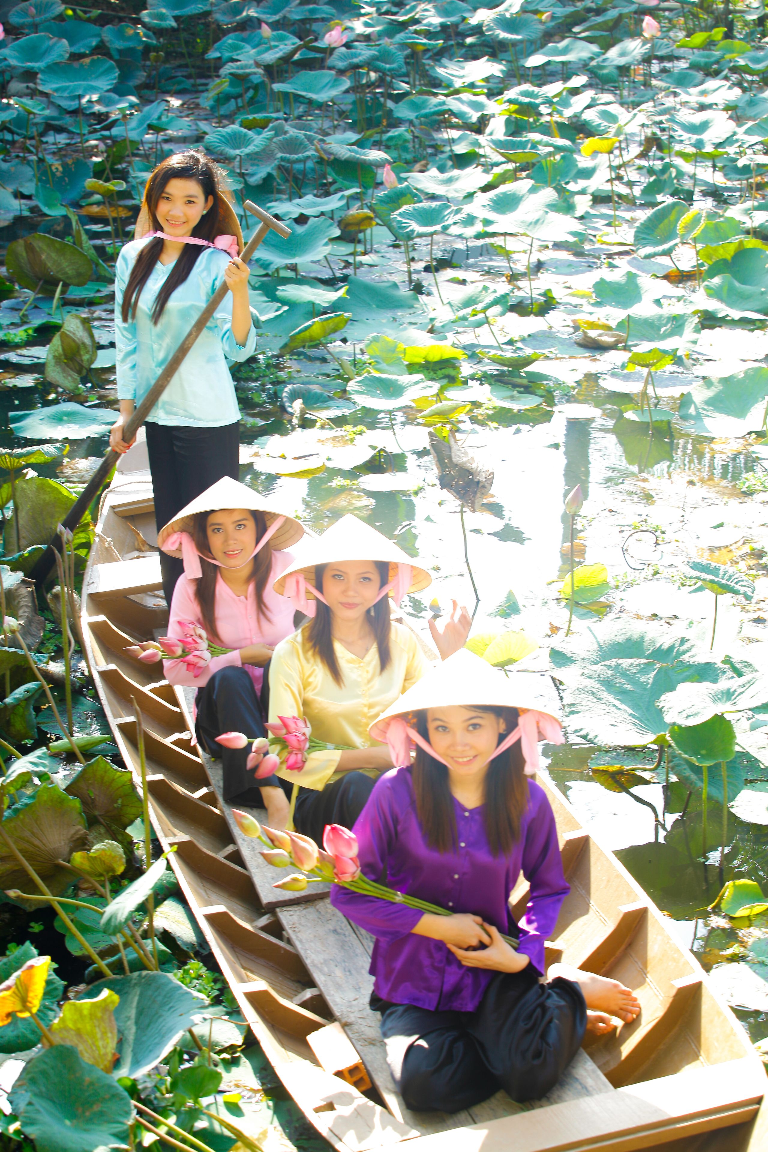 A boat with passengers wearing conical hats, surrounded by water lilies.