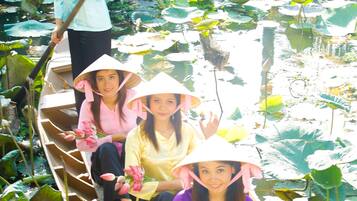A boat with passengers wearing conical hats, surrounded by water lilies.