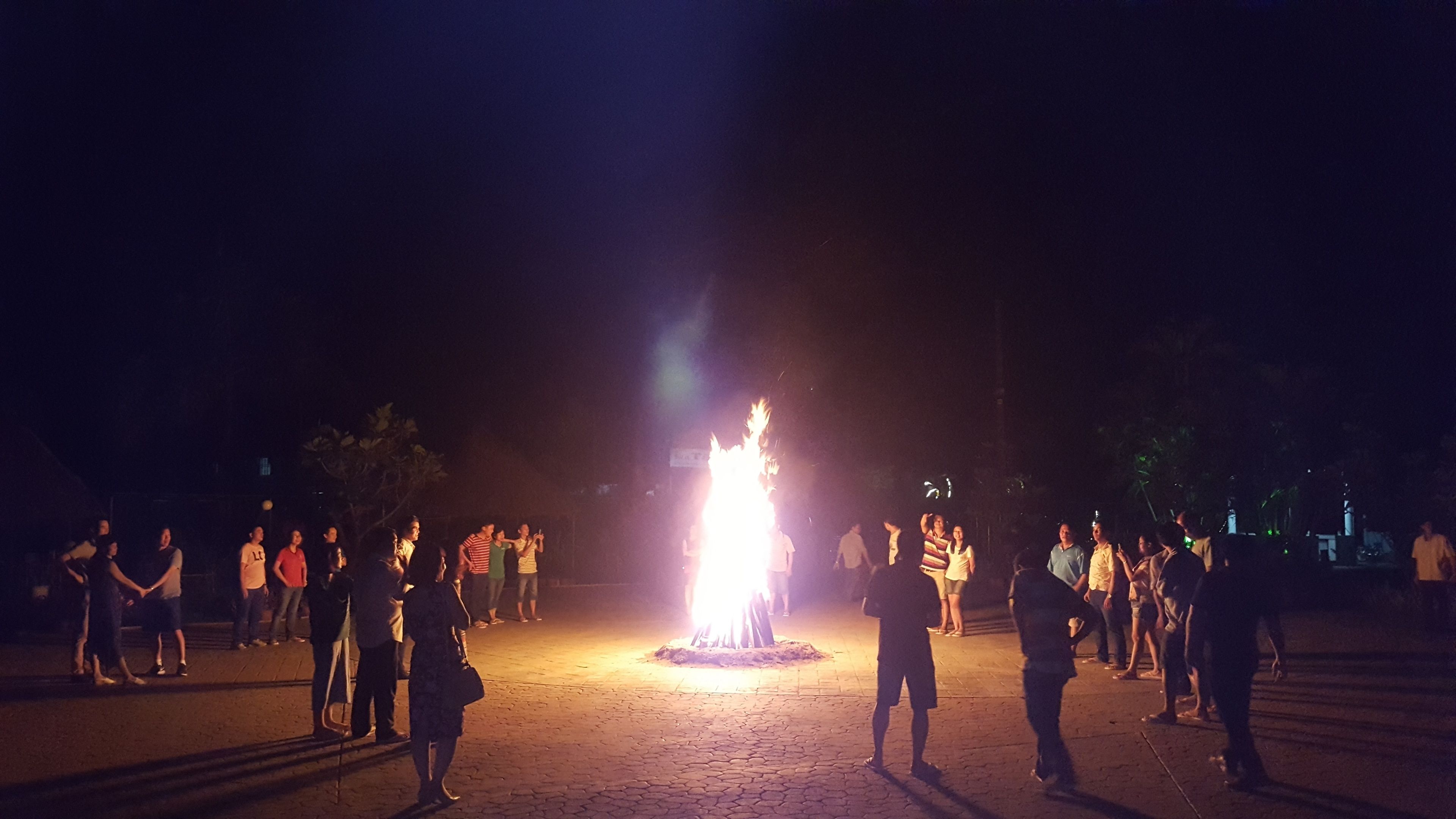 Un grupo de personas reunidas alrededor de una fogata, posiblemente para una ceremonia o evento.