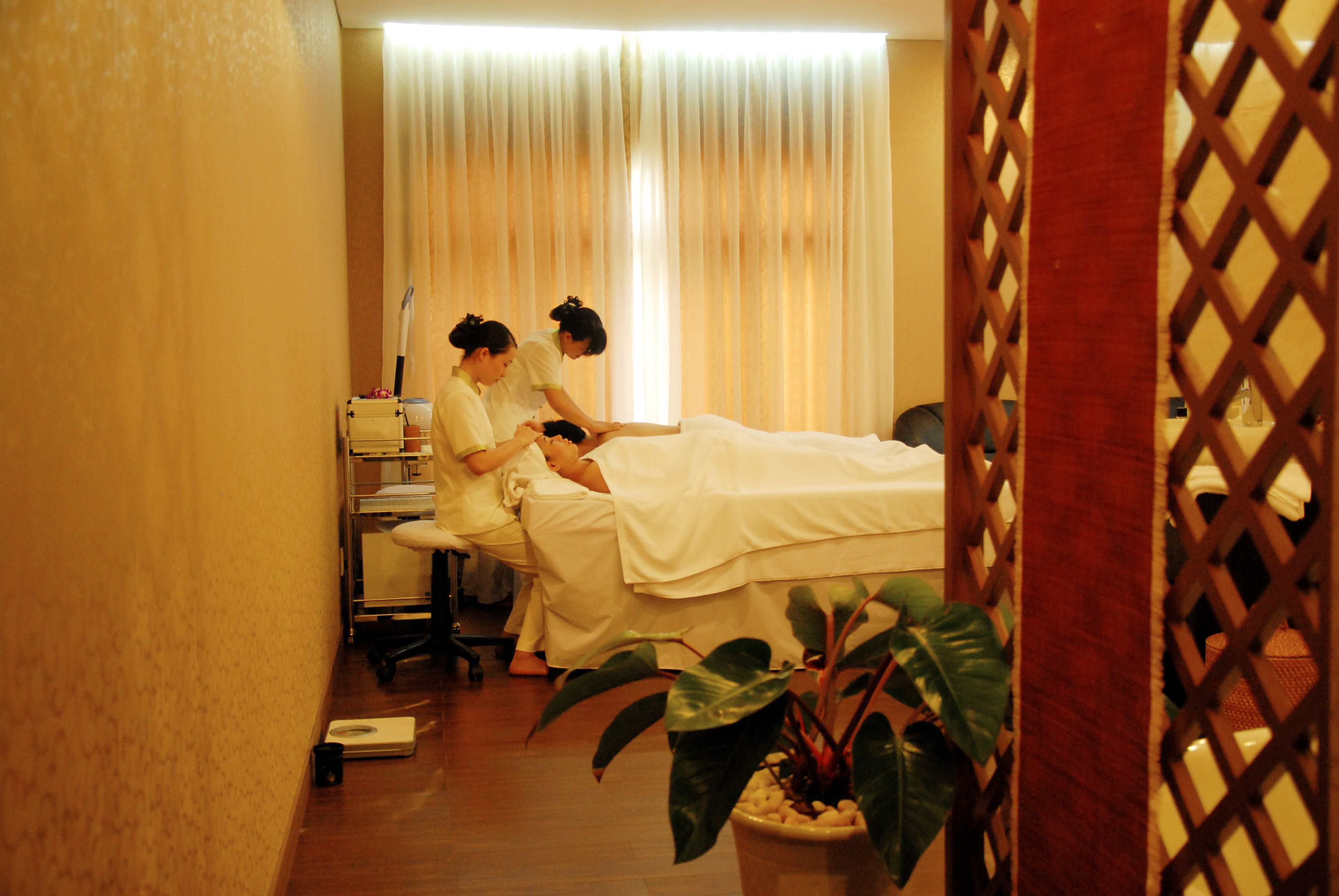 A room with a bed, a massage table, and a person receiving a massage.