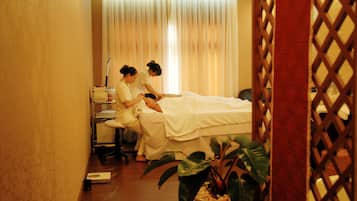 A room with a bed, a massage table, and a person receiving a massage.