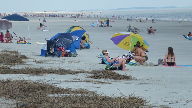 A beach with tents and umbrellas, people relaxing, and a clear view of the sea. - "Couples & Family Getaway," 1st Floor, King & Queen Beds, Pool, 42" HDTV's, WIFI (Hilton Head Island)