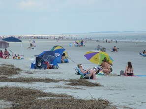 A beach with tents and umbrellas, people relaxing, and a clear view of the sea.