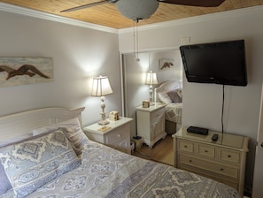 Una camera da letto con un letto, comodini, una lampada, una TV e uno specchio.