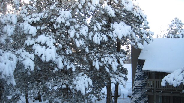 A snow-covered lodge with a wooden deck and a picnic table.
