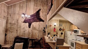 A rustic interior with a dining area, kitchen, and a mounted animal hide.