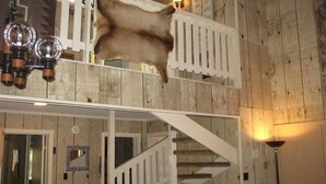 A room with a wooden staircase, a hanging light fixture, and a mounted animal hide.