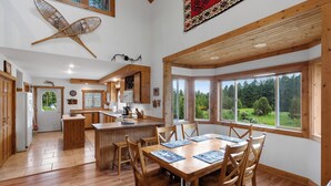 A spacious kitchen with wooden cabinets, a central island, and large windows offering a view of the outdoors. - Yellowstone Mountain Home-Secluded custom home near Yellowstone with privacy! (Emigrant)
