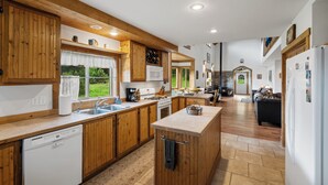 A spacious kitchen with wooden cabinets, a central island, and a view of the outdoors. - Yellowstone Mountain Home-Secluded custom home near Yellowstone with privacy! (Emigrant)