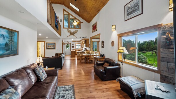 A spacious living area with a wooden ceiling, a large window with a view of the outdoors, and a cozy seating arrangement. - Yellowstone Mountain Home-Secluded custom home near Yellowstone with privacy! (Emigrant)