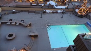 Un área de piscina en la azotea con un jacuzzi, sillones de descanso y un árbol de Navidad.