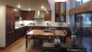 Una cocina moderna con armarios de madera oscura, electrodomésticos de acero inoxidable y una amplia mesa de comedor con sillas.