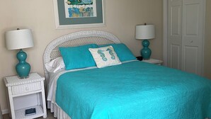A bedroom with a bed, two nightstands, a ceiling fan, a door, and a framed picture on the wall. - Panoramic Ocean & Sound Views, 2 min walk to beach, Sleeps 8-10, Emerald Isle (Emerald Isle)
