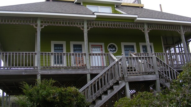 A two-story building with a balcony and a wooden staircase leading to the upper floor. - Panoramic Ocean & Sound Views, 2 min walk to beach, Sleeps 8-10, Emerald Isle (Emerald Isle)