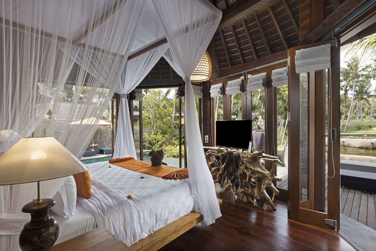 A room with a bed, a TV, and a view of the outdoors.