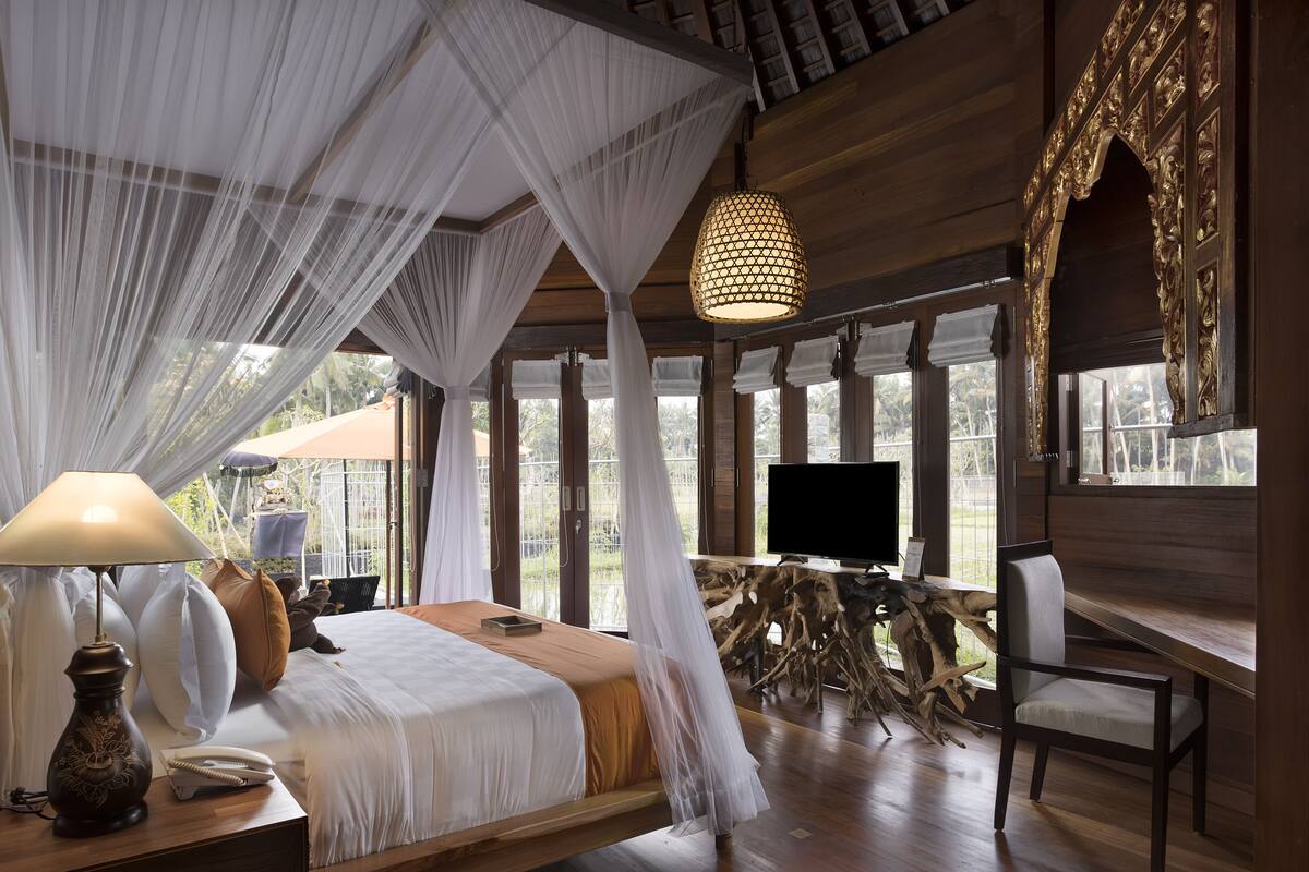 A bedroom with a bed, bedside table, lamp, and a television.