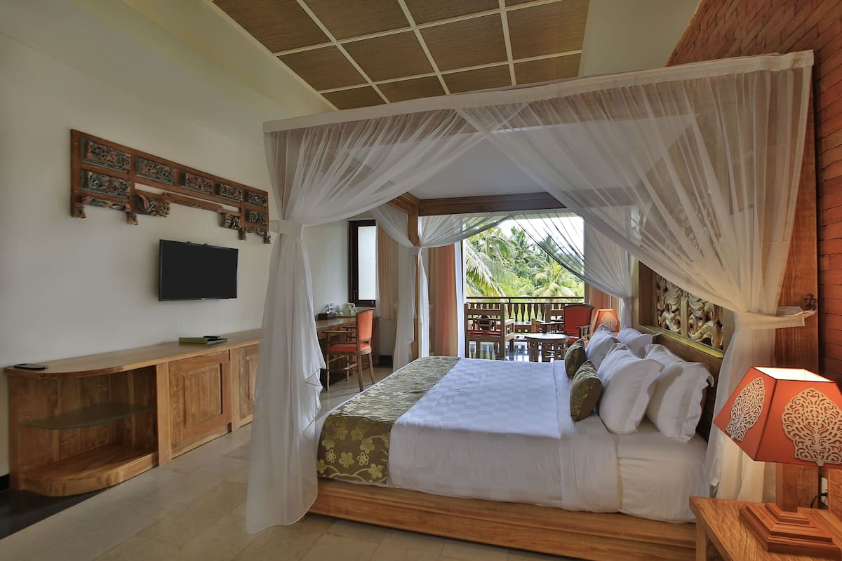 A bedroom with a canopy bed, a TV mounted on the wall, and a balcony with outdoor seating.