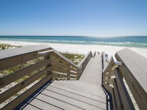 A wooden boardwalk leading to a beach with clear skies.