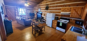 A cozy cabin interior with a dining area, kitchen, and living room.