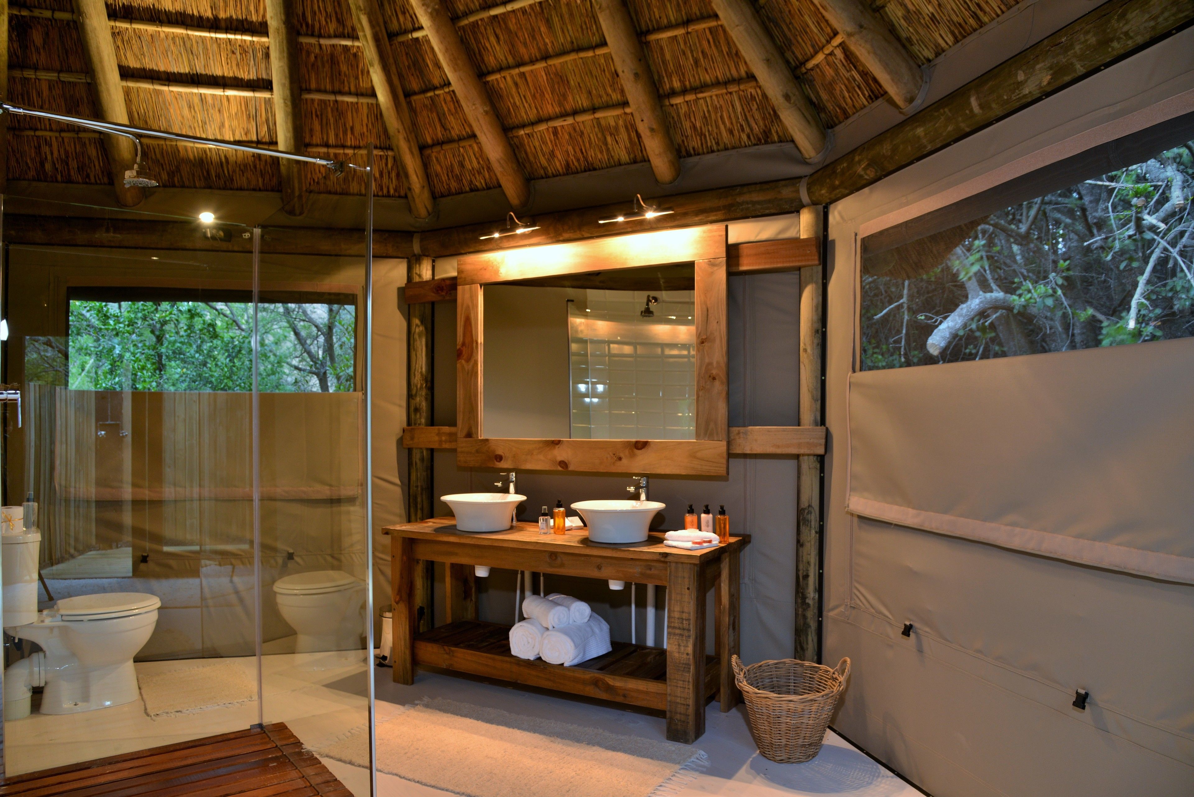 A bathroom with a wooden vanity, two sinks, a large mirror, and a glass shower enclosure.