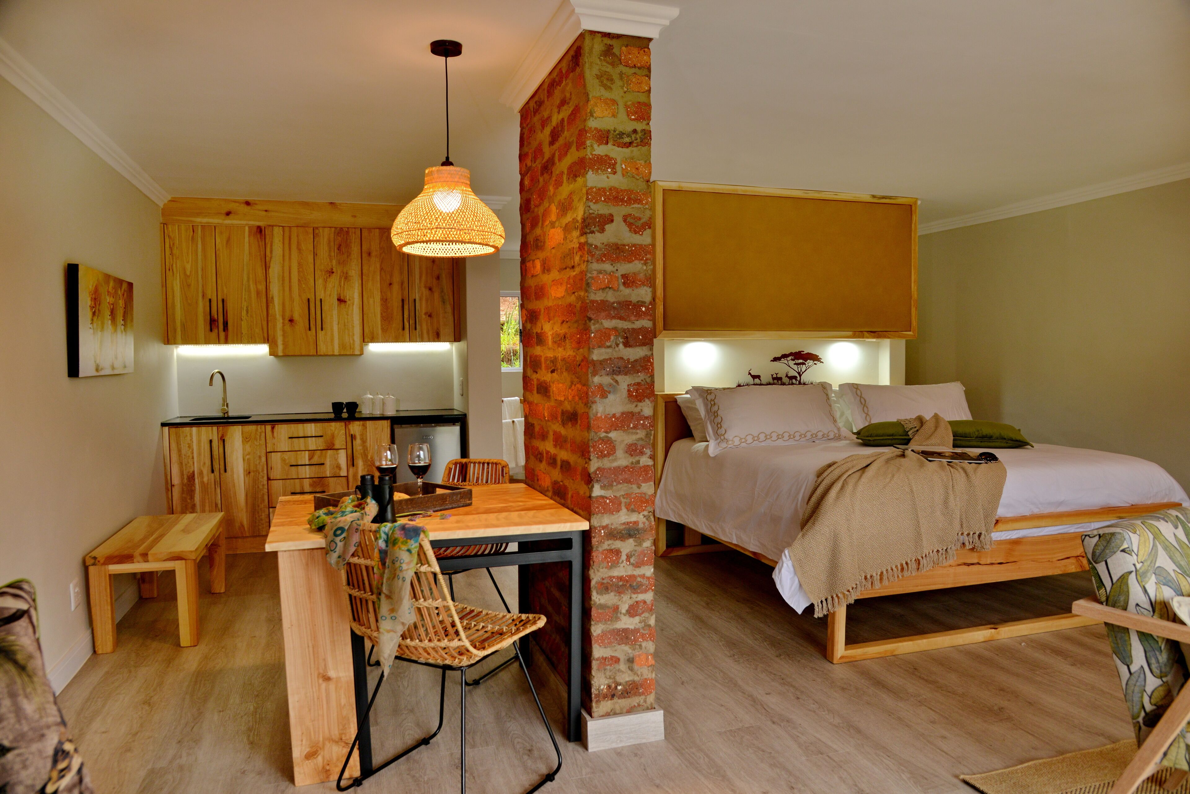 A compact room with a bed, a dining table, and a kitchen area.