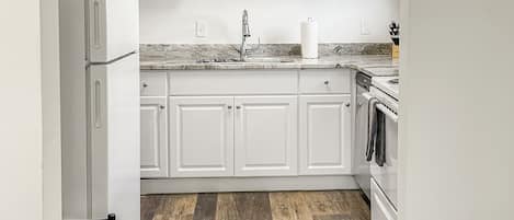A kitchen with white cabinets, a stainless steel refrigerator, a microwave, and a stove.
