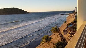 A beach view with a building on the right, a sandy beach, and waves.