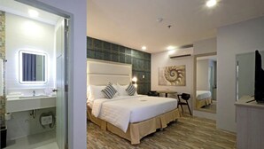 A modern hotel room with a large bed, a bedside table, a mirror, and a bathroom with a sink and toilet. - Amethyst Boutique Hotel Cebu powered by Cocotel (Cebu City)