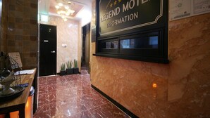 A marble-floored lobby with a reception desk and a wall-mounted information board for the Legend Motel. - Legend Motel (Geoje)