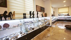 A museum with glass display cases containing various artifacts and sculptures. - Legend Motel (Geoje)
