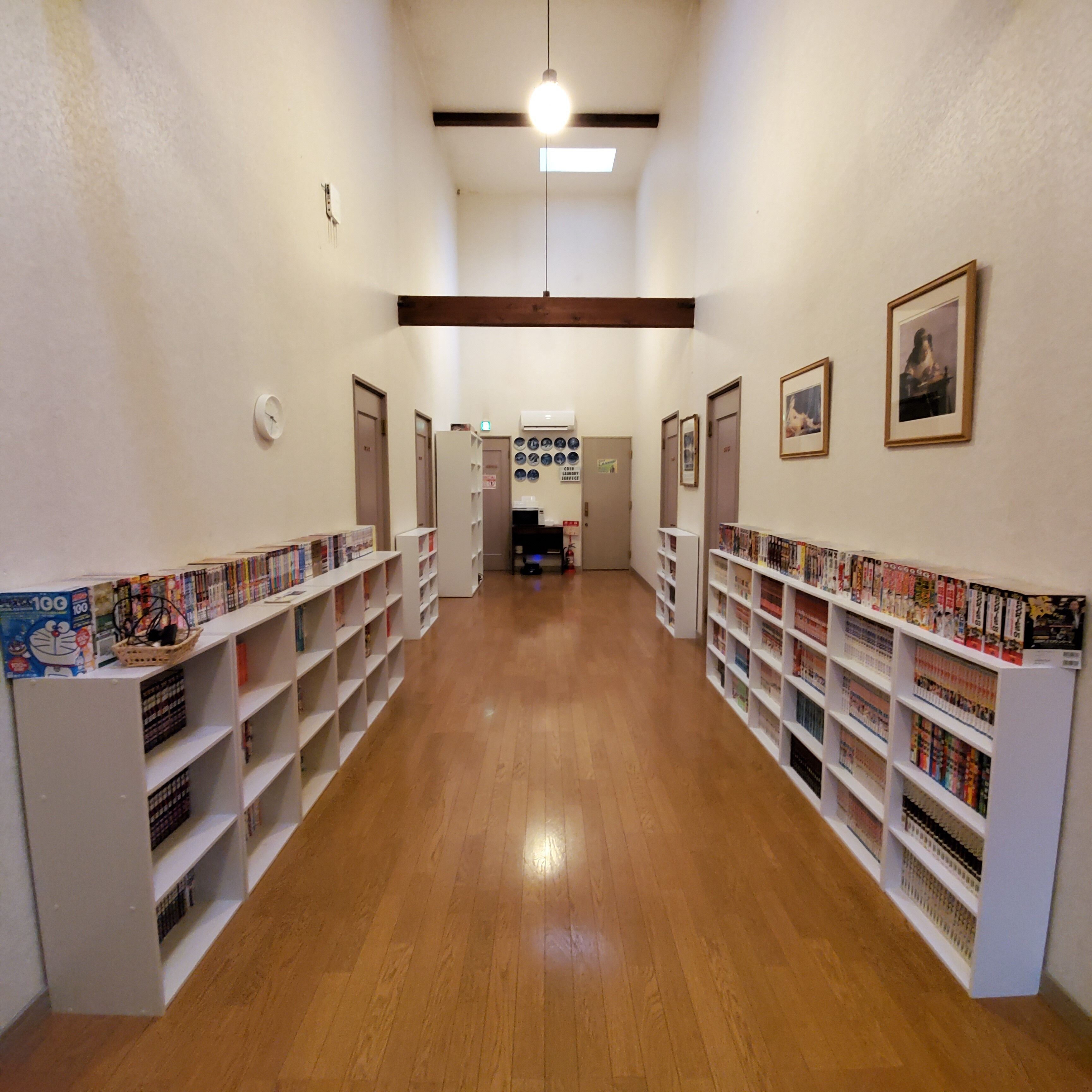 Ett bibliotek med trägolv och vita bokhyllor fulla av böcker.